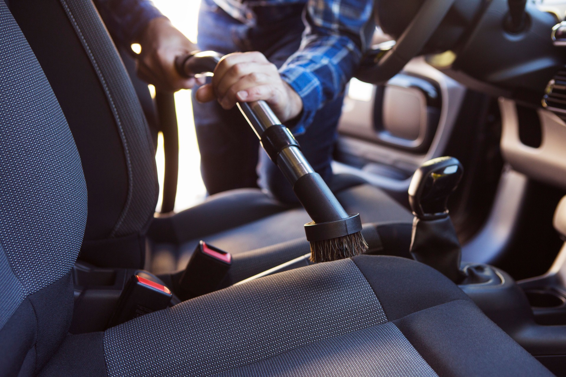 Man Hoovering Seat Of Car During Car Cleaning